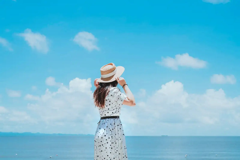 Mujer en la playa viendo hacia el horizonte